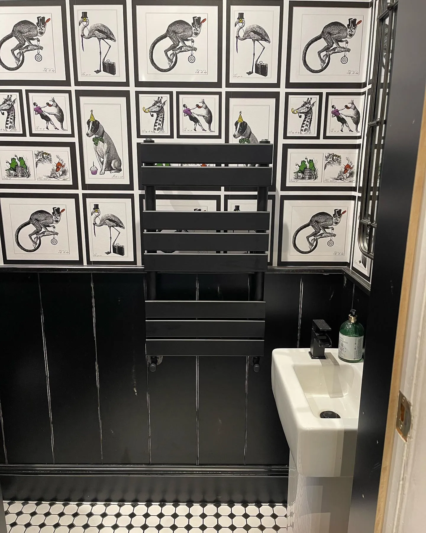 A bathroom with black and white wallpaper and a sink.