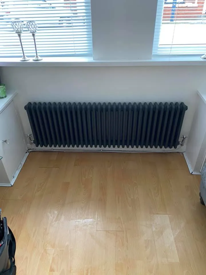 A room with a radiator and a suitcase on the floor.