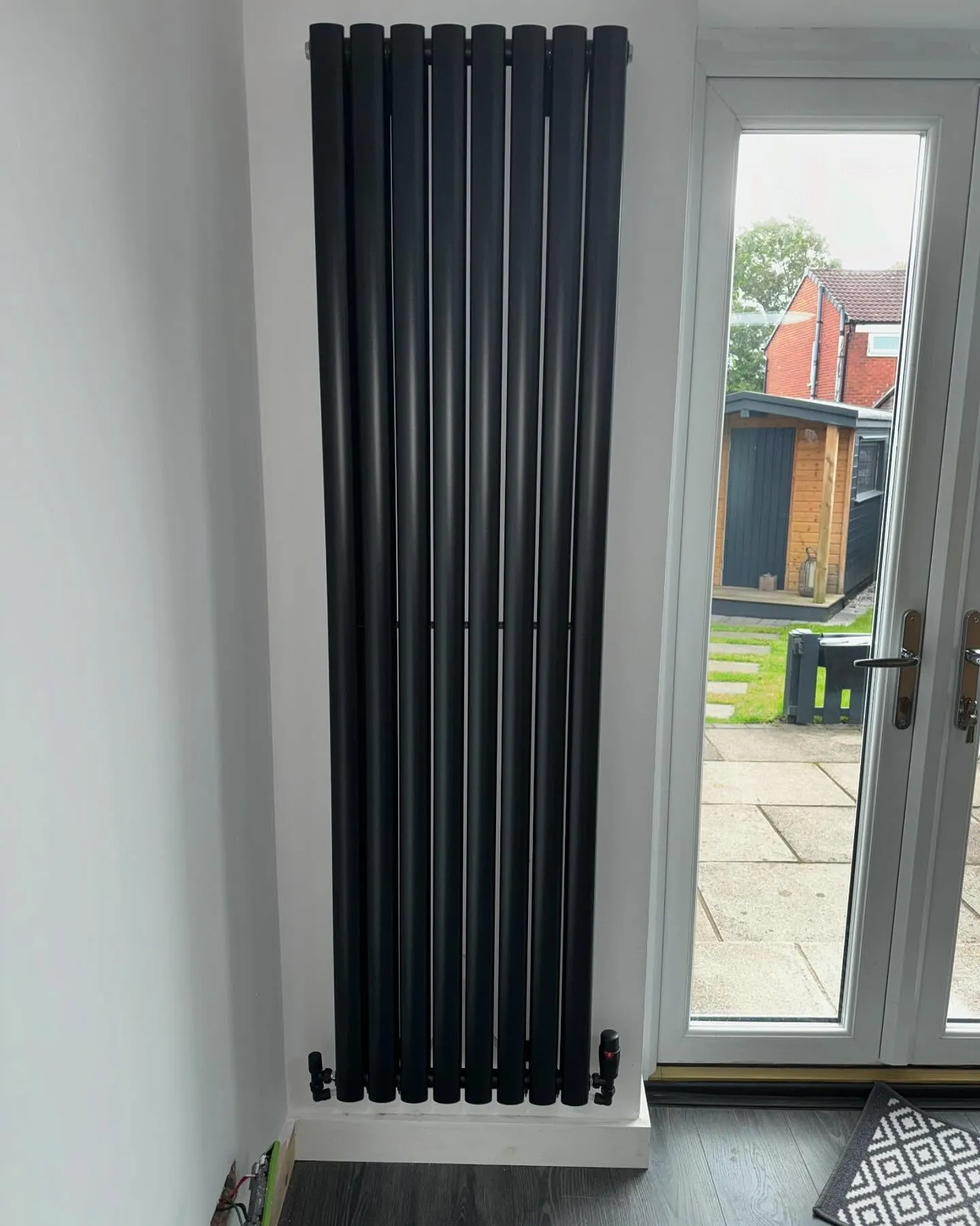 A black radiator in front of a sliding glass door.