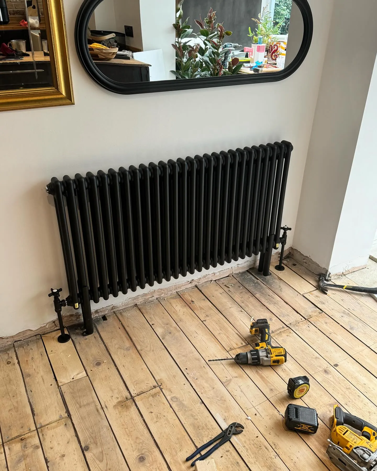 A room with a radiator and tools on the floor.