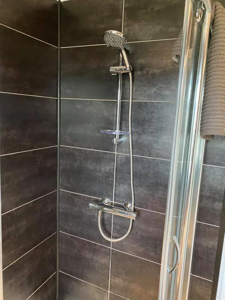 A walk in shower next to a toilet in a bathroom.